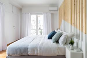 a white bedroom with a large bed and a window at Acropolis Core Bright & Modern Apartment by UPSTREET in Athens