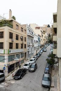 a city street with parked cars and buildings at Acropolis Core Bright & Modern Apartment by UPSTREET in Athens