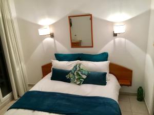 Schlafzimmer mit einem Bett mit blauen und weißen Kissen in der Unterkunft STUDIO or ONE BEDROOM Avenue de la plage in Roquebrune-Cap-Martin