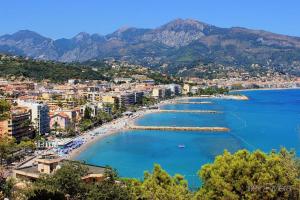 Blick auf einen Strand mit Gebäuden und Bergen in der Unterkunft STUDIO or ONE BEDROOM Avenue de la plage in Roquebrune-Cap-Martin