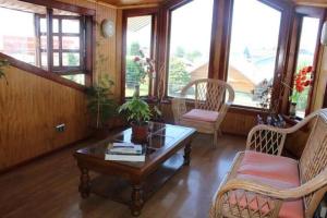 sala de estar con mesa, sillas y ventanas en Hostal Lagunitas en Puerto Montt