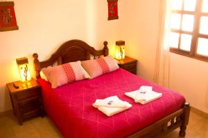 a bedroom with a red bed with two towels on it at Hostal Tacacho in Iruya