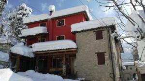 una casa roja con nieve encima en Il Piccolo Granaio, en Scavolino