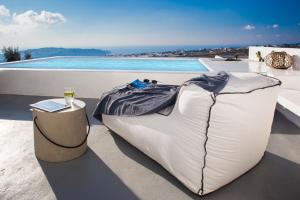 a bed sitting on a balcony with a glass of wine at Alunia Incognito Suites - Adults Only in Pirgos