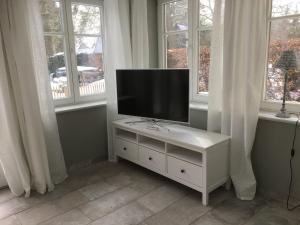 a tv on a white cabinet in a room with windows at Wolffs-Idyll in Prerow