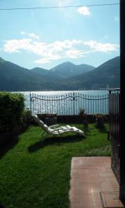 a bench sitting on the grass near a body of water at Appartamento monteisola mara in Monte Isola
