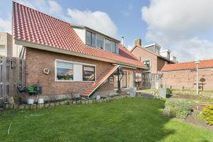 a brick house with a red roof and a yard at Spacious Family Home Halfweg in Halfweg