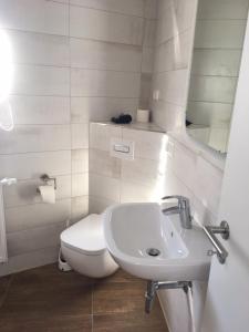 a white bathroom with a toilet and a sink at Ferienhaus an der Selke in Meisdorf