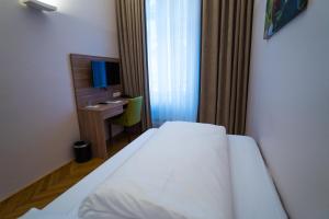 Un dormitorio con una cama y un escritorio con televisión. en Hotel Marc Aurel - Vienna City Center, en Viena