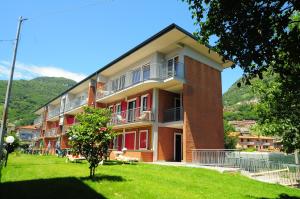 un edificio de ladrillo rojo con un patio verde en Residence Windsurf, en Domaso