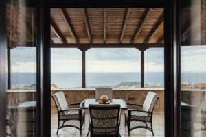 una mesa y sillas en un balcón con vistas al océano en Lena's Villa, en Stoupa