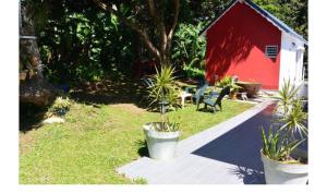un jardín con un cobertizo rojo, un banco y una casa en Bungalow Bambou, en Petit-Bourg