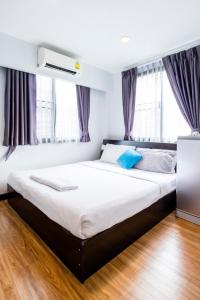 een slaapkamer met een groot bed met witte lakens en blauwe kussens bij The Cube Sathorn Boutique Hotel เดอะ คิวบ์ สาทร บูติค โฮเทล Near BTS Surasak in Bangkok