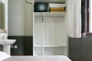 1 dormitorio con armario blanco y TV. en Hotel Residenza - 400m do inicio da Av Paulista e Metrô Paraiso, en São Paulo