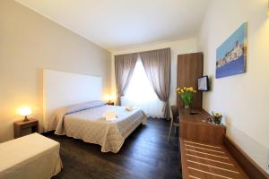 a bedroom with a bed and a desk and a window at B&B Al Picchio in Monopoli