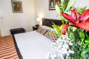 a bedroom with a bed and a vase of flowers at Hotel Mendoza in Mendoza