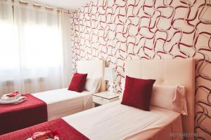2 Betten in einem rot-weißen Zimmer in der Unterkunft Alcam Badalona Playa Norte in Badalona