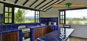 a kitchen with blue tiled walls and windows and a counter at Hacienda Veracruz villa de leyva in Villa de Leyva
