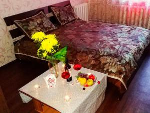SalavatにあるАтмосфера Уютのベッド1台、テーブル(ドリンク、花付)が備わる客室です。