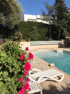 une chaise blanche à côté d'une piscine avec des fleurs roses dans l'établissement Villa Bruyere, à Antibes