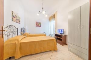 una camera con letto giallo e televisore di Salento Sweet Home a Melissano