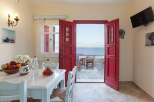 a dining room with a red door leading to the ocean at Villa Athina in Ambrami