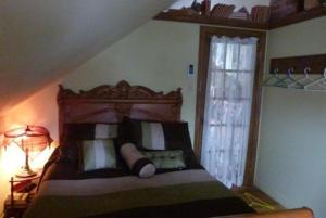 een slaapkamer met een bed, een lamp en een raam bij Vieille École du Rang 3 in Saint-Henri-de-Taillon