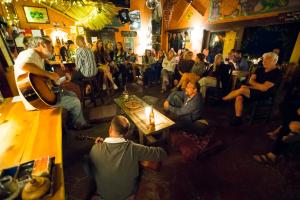 a group of people sitting in a bar playing music at La Iguana Perdida in Santa Cruz La Laguna