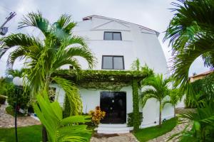 a white house with palm trees in front of it at Sereia do Mar Pousada e Restaurante Ltda in Jacumã
