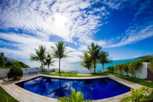a swimming pool with palm trees and the ocean at Sereia do Mar Pousada e Restaurante Ltda in Jacumã