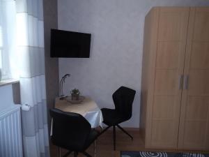 a room with a table and two chairs and a television at Zimmer Schmitz in Anschau