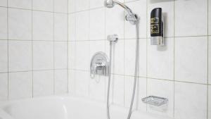 y baño de azulejos blancos con ducha y manguera. en Entenwirt Seeham en Seeham