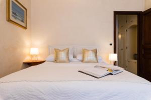 a bedroom with a white bed with a book on it at VILLA EUGENIA - Luxury Flat in the Centre, with Parking Space in Bordighera