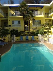 a swimming pool in front of a hotel with chairs and a building at Magic Castle Hotel in Los Angeles