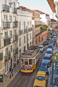 a yellow tram on a city street with cars at Old Town Loft in Lisbon