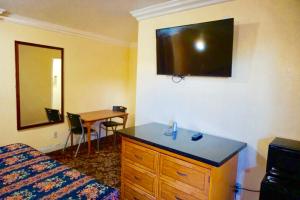 Habitación de hotel con cama y tocador con espejo en Satellite Motel, Los Angeles - LAX, en South Los Angeles