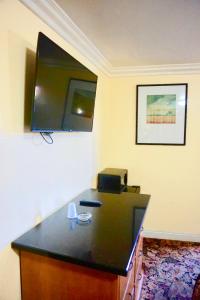 Habitación con escritorio y TV en la pared. en Satellite Motel, Los Angeles - LAX, en South Los Angeles