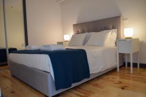 una camera da letto con un grande letto con lenzuola e cuscini bianchi di Suite In a Porto