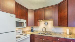 a kitchen with wooden cabinets and a white appliance at Tropical Paradise at Diplomat in Cocoa Beach