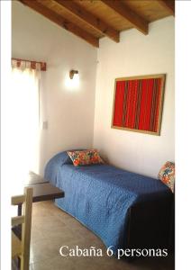 a bedroom with a blue bed and a table at Cabañas Club del Lago in La Falda