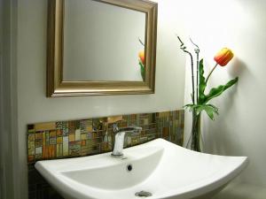 a bathroom sink with a mirror and a vase with flowers at Prosperity Inn in Vigan