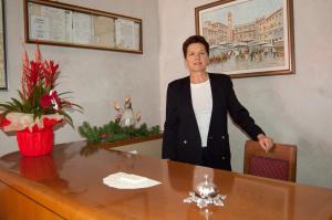 グレッツァーナにあるHotel Marchesiniの女がテーブルの横に立っている