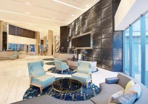 a lobby with chairs and a table and a tv at Novotel Samator Surabaya Timur in Surabaya