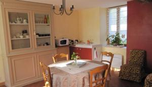 ein Esszimmer mit einem Tisch und einer Küche in der Unterkunft Chambres d'hôtes - La rose des champs in Lachelle