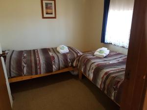 two twin beds in a room with a window at Windana Cottages in Hawker