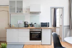 a kitchen with white cabinets and a counter with a microwave at Herse - Corsaire in Saint Malo