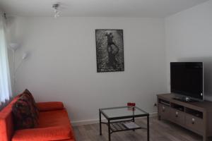 sala de estar con sofá naranja y TV en Tango Ferienwohnung Winnenden, en Winnenden