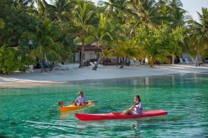 two people in kayaks in the water near a beach at Diamonds Athuruga Maldives Resort & Spa in Athuruga Island