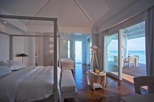 a bedroom with a bed and a view of the ocean at Diamonds Athuruga Maldives Resort & Spa in Athuruga Island