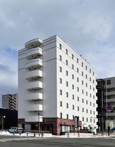 a large white building on a city street at Hotel JIN Morioka Ekimae in Morioka